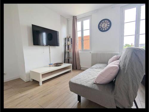 un salon avec un canapé et une horloge au mur dans l'établissement maison, à Martot