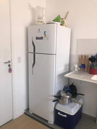 a white refrigerator in a kitchen next to a shelf at 06 - Apto Studio Liberdade Sé 500'Metrô in Sao Paulo
