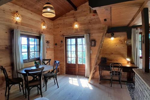 - une salle à manger dans une cabane en rondins avec une table et des chaises dans l'établissement Petit chalet authentique, à La Blonnière