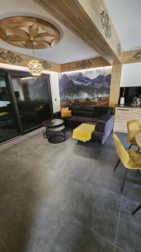 a living room with a couch and a table and chairs at Porębiańska Osada Resort & Spa in Szlembark