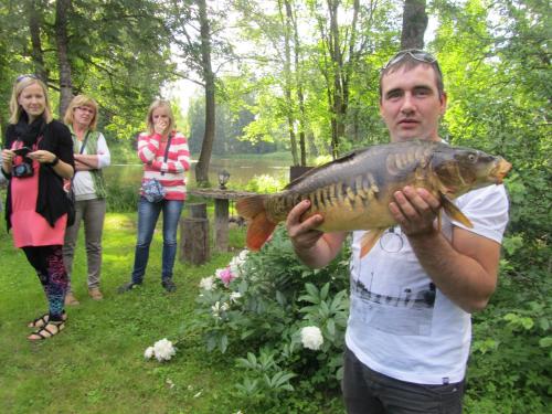 a man holding a fish in front of a group of people at Kučuru dzirnavas in Lautere