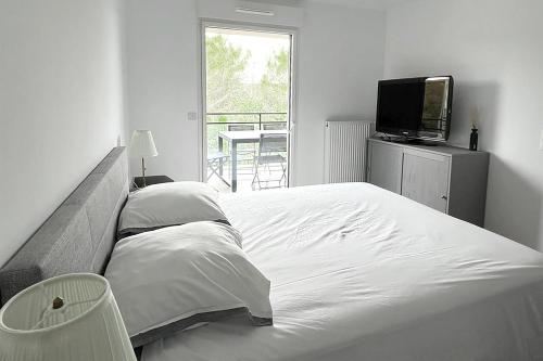 une chambre blanche avec un lit et une télévision dans l'établissement Charmant 2 pièces avec belle terrasse à Valbonne, à Valbonne