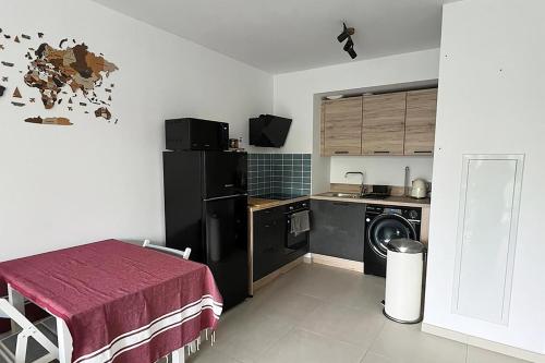 Il comprend une cuisine équipée d'un réfrigérateur noir et d'un lave-linge. dans l'établissement Charmant 2 pièces avec belle terrasse à Valbonne, à Valbonne