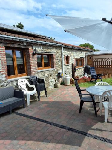a patio with chairs and tables and a white umbrella at Le petit nid in Brugelette