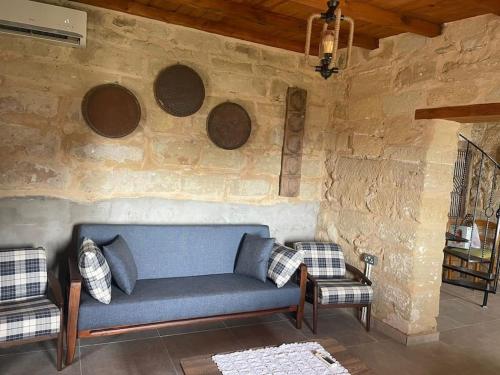 a living room with a blue couch and a stone wall at King's Hill Traditional House in Galinoporni