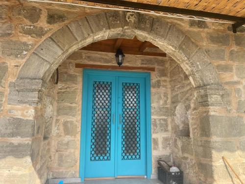 a blue door on a stone building with an arch at King's Hill Traditional House in Galinoporni