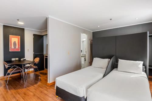 a hotel room with two beds and a table at Slaviero São Paulo Ibirapuera in Sao Paulo