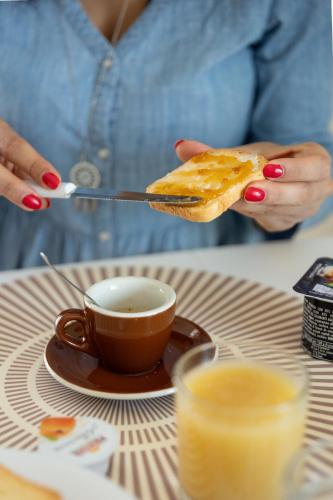 a woman holding a piece of toast and a cup of coffee at B&B Sila in Fiore in San Giovanni in Fiore