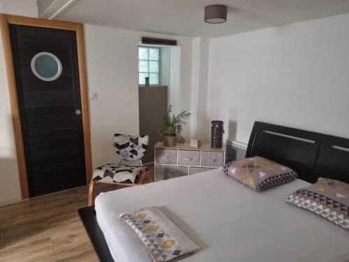 a bedroom with a bed with a black door and a chair at Tournus Castrum Romain - Duplex 54 m2 - 3 Étoiles - petit box vélo - 5mn Autoroute in Tournus
