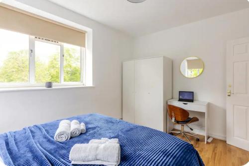 a bedroom with a blue bed with towels on it at Spacious Two Bedroom Apartment in Battersea, Free Parking in London