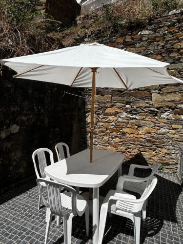a white table and chairs with an umbrella at Free Spirit in Vale do Torno