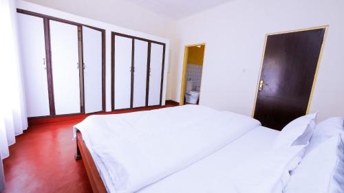 a white bed in a room with large windows at Inkindi House in Kigali