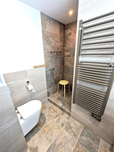 La salle de bains est pourvue de toilettes et d'un tabouret jaune. dans l'établissement Chalets Du Thabor - 3 pièces 6/8 personnes pied piste MAE-0291, à Modane