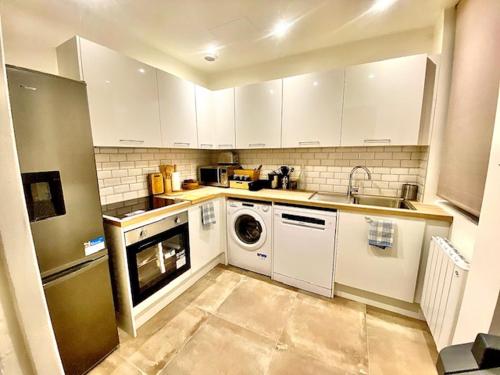 une cuisine avec des armoires blanches et une laveuse et une sécheuse dans l'établissement Appart in Paris, à Pantin