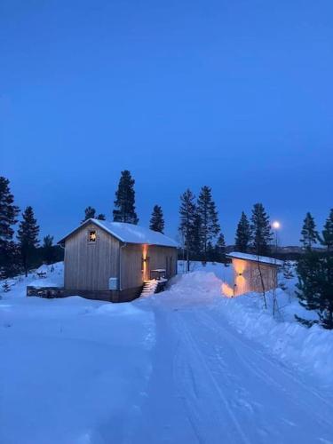 a building in the snow at night with lights on at Wonderful barn cabin in Järvsö Harsa in Järvsö