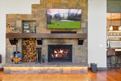 a living room with a fireplace with a tv above it at Snowghost Chalet Ultimate Luxury Ski In Ski Out 5BD 55BA with Hot Tubs Steam Room and Game Room in Whitefish