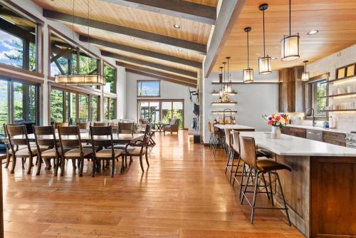 a dining room with tables and chairs and windows at Snowghost Chalet Ultimate Luxury Ski In Ski Out 5BD 55BA with Hot Tubs Steam Room and Game Room in Whitefish