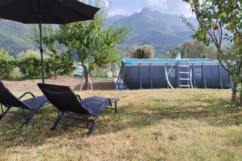 two chairs and an umbrella in a yard with a tub at Casa Sant'Anna - In Garfagnana - Happy Rentals in Minucciano