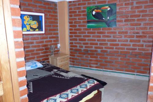 a room with a brick wall with a bed in it at Hostal La Casa Amarilla City in Baños