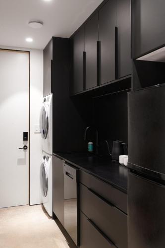 a kitchen with black cabinets and a washer and dryer at Coldbrook Bed and Breakfast in Bearsville