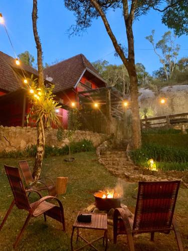 a fire pit in a yard with two chairs and a table at Casa da Pedra Atibaia Clube da Montanha in Atibaia
