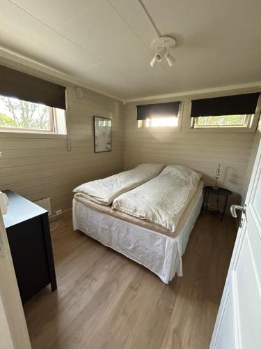a bedroom with a bed and two windows at Nyoppusset sokkelleilighet med bra bussforbindelser in Kvaloysletta