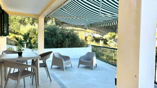 a patio with a table and chairs on a balcony at Casa da Oliveira, Aradas, Pampilhosa da Serra, Wifi, Ar Condicionado, Churrasqueira, Parqueamento, by IG in Unhais-o-Velho