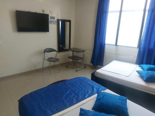 a room with two beds and a desk and a television at Hotel Perla Azul Boutique in Girardot