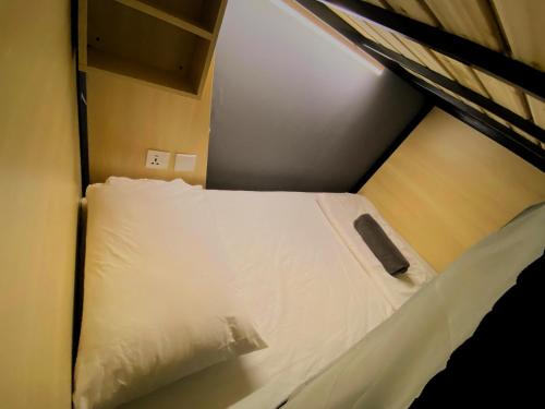 a bed with white sheets and pillows in a room at Travelogue Guest House in Kuala Lumpur