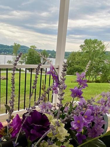 a vase of purple flowers sitting on a porch at Gray's Manor - Lake Memphremagog in Newport