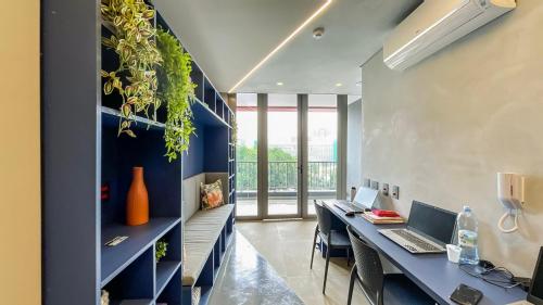 an office with two desks with laptops and a plant wall at 360 VN Turiassú by Housi in Sao Paulo