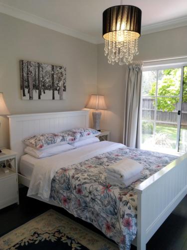 a bedroom with a bed with a chandelier and a window at Magnolia Corner in Bowral
