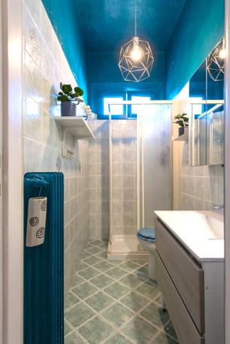 a blue bathroom with a shower and a toilet at Hostly-Ai Due Passi Apartment in Pisa