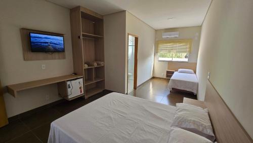 una camera da letto con un letto e una TV a parete di Hotel Habitar Serra do Salitre MG a Serra do Salitre