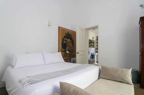 a bedroom with a large white bed and a chair at Bohemian Villa in heart of Barranco in Lima