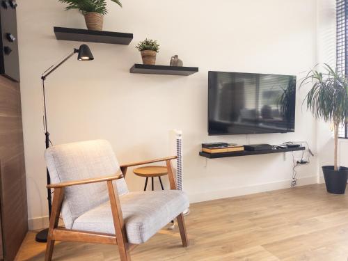 a living room with a chair and a tv on a wall at De Schelp 86, Garden and Free parking in Zandvoort
