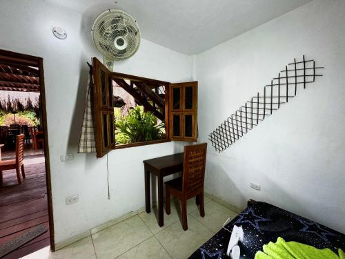 a room with a table and a window and a fan at Hostal Nibuni Palomino in Palomino