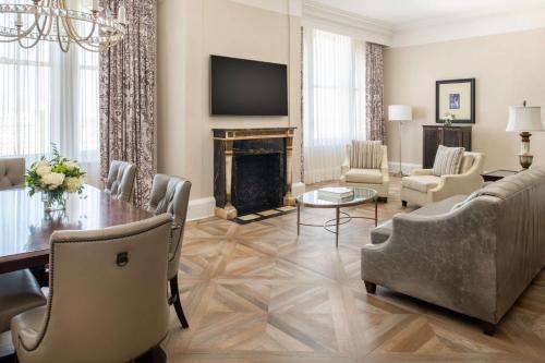a living room with a table and a fireplace at The Roosevelt Hotel New Orleans - Waldorf Astoria Hotels & Resorts in New Orleans