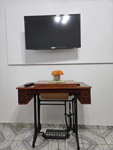 a wooden desk with a tv on a wall at Casa Groot in Holambra