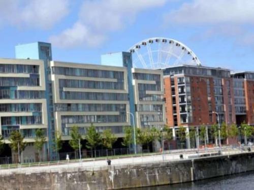 a large building with a ferris wheel in the background at Dockside Aparthotel, Best Western Signature Collection in Liverpool