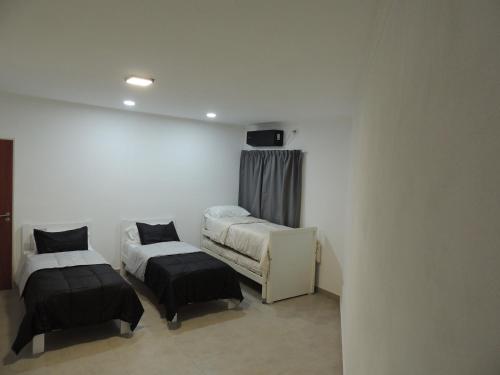 a room with two beds and a tv on the wall at El Refugio de Salvador in Paraná