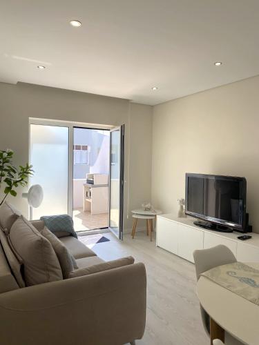 a living room with a couch and a flat screen tv at Barra Azul - Beach Apartment in Praia da Barra