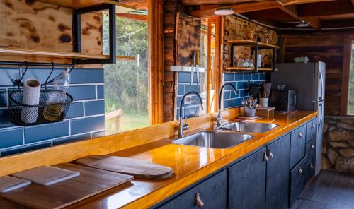 a kitchen with two sinks and a window at Preciosa Cabaña privada, BBQ, salón de juegos, cine! in El Líbano