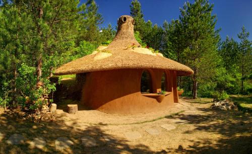 a small hut with a grass roof in a field at Omaya Eco Village in Gaytaninovo