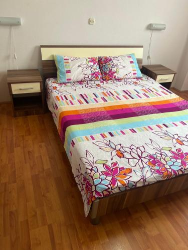 a bed with a colorful comforter and two night stands at Mario in Ohrid