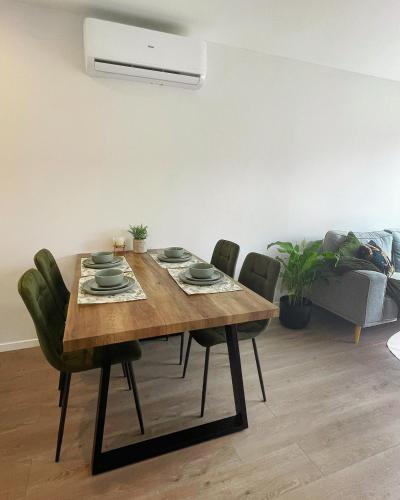a dining room table with green chairs around it at Brand New Modern 2BR Townhouse in Auckland