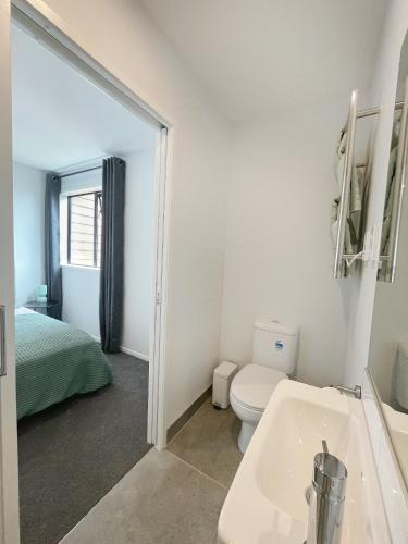 a bathroom with a sink and a toilet and a bed at Brand New Modern 2BR Townhouse in Auckland