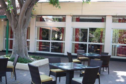 a patio with tables and chairs and a tree at Cresta Bosele Hotel in Selebi-Pikwe