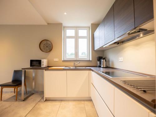 a kitchen with white cabinets and a sink and a window at Achter de Hegge in Riemst