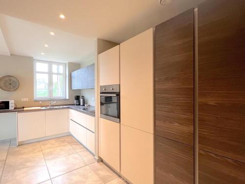 a kitchen with white and wooden cabinets and a stove at Achter de Hegge in Riemst